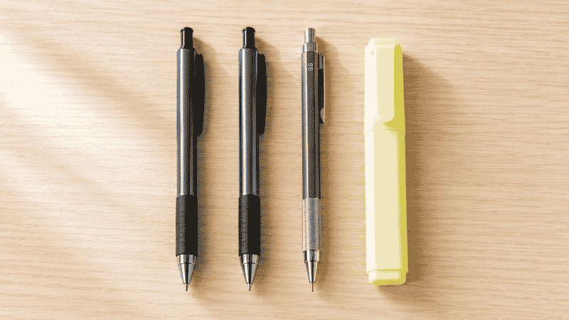 A small curated selection of essential writing tools for a home office including two pens, a pencil, and one highlighter arranged neatly