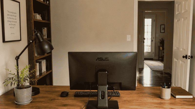 A home office desk positioned facing the room entrance in the command position with a solid wall behind it