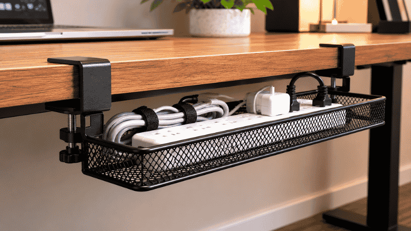 A clamp-mount cable tray attached to the edge of a desk without drilling showing the clamp mechanism gripping the desk edge