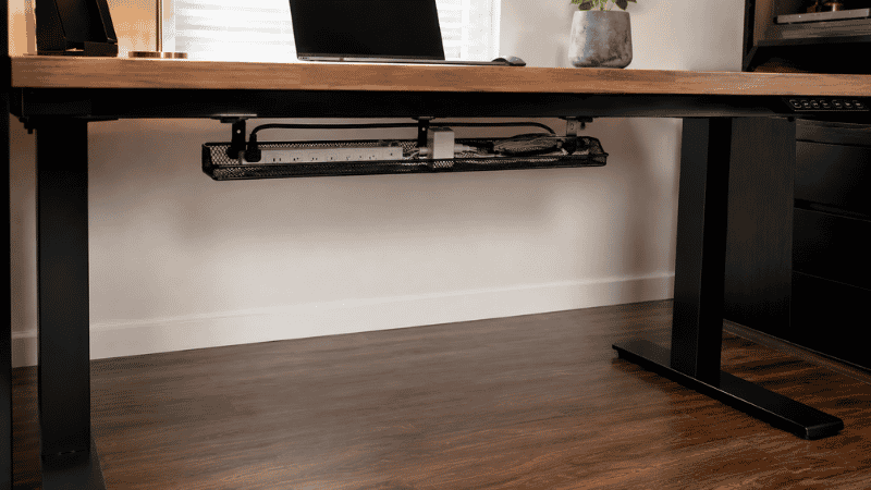 The space under a desk after cable tray installation showing a completely clear floor with all cables and power strip contained in the mounted tray above