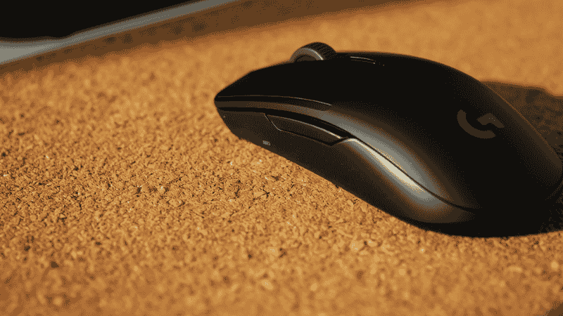 A close-up, detailed shot of the natural grain texture of a sustainable cork desk mat with a Logitech MX Master 3S mouse, highlighting the smooth tracking surface.