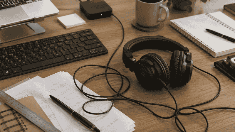 Headphones lying flat on a desk surface taking up space and adding to desk clutter showing the problem a headphone stand solves