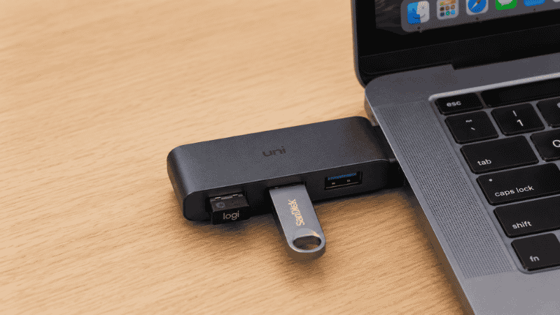 A USB-C docking station on a desk with a single cable connecting to a laptop, showing all peripherals connected through the dock including monitor and keyboard